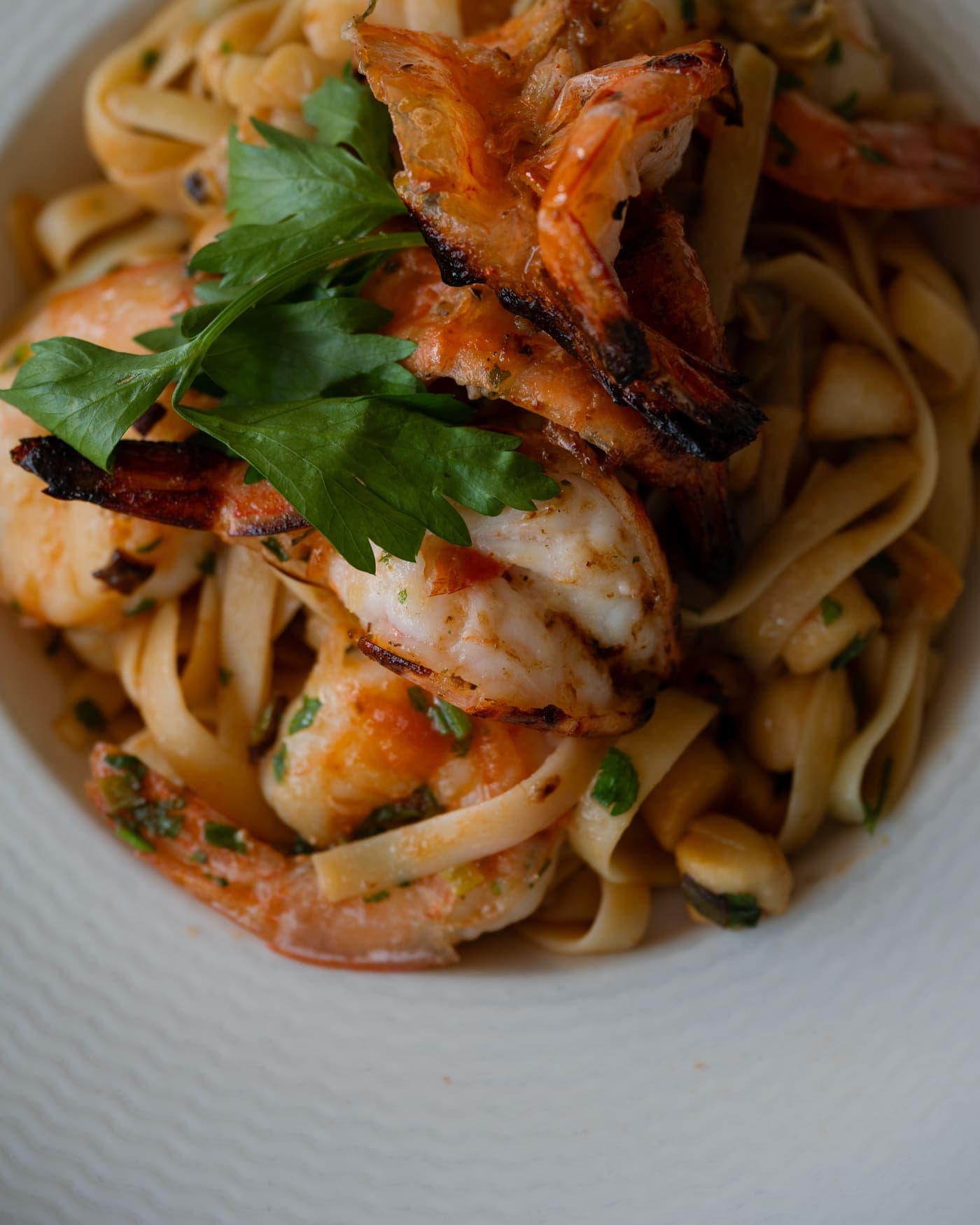 Fettuccine topped with grilled shrimp and fresh parsley