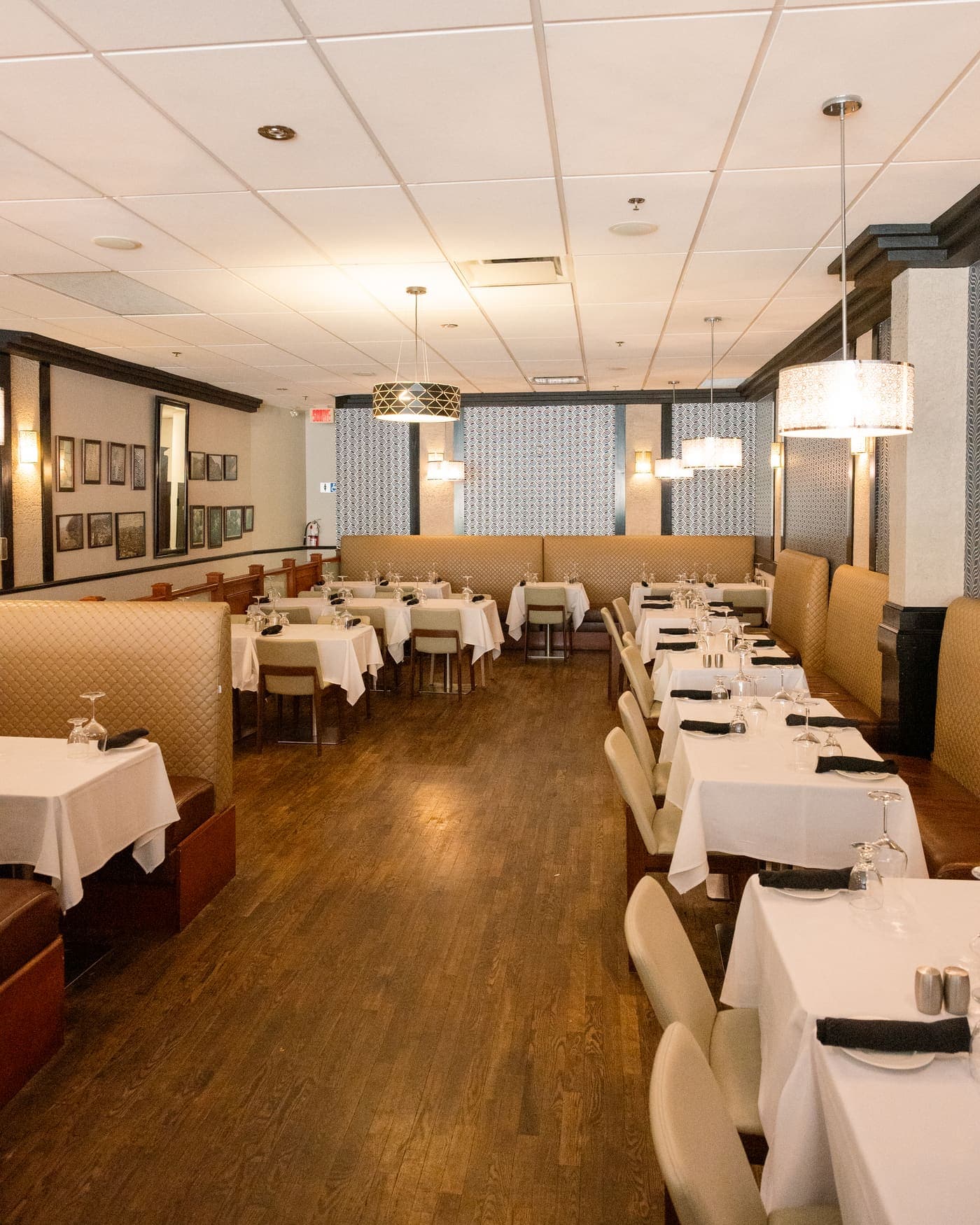 The dining room: quilted beige banquettes, white-clothed tables and pendant lights