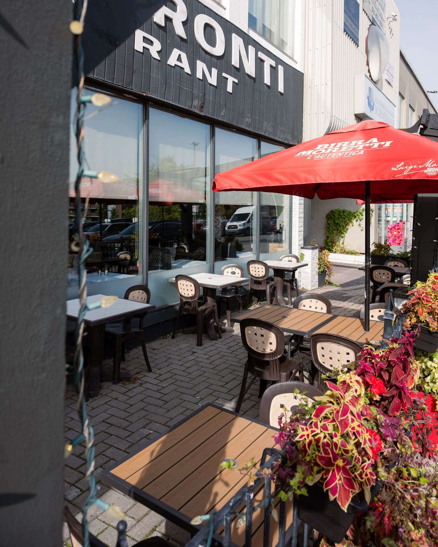 The terrace out front: wooden tables, a red umbrella and flower boxes